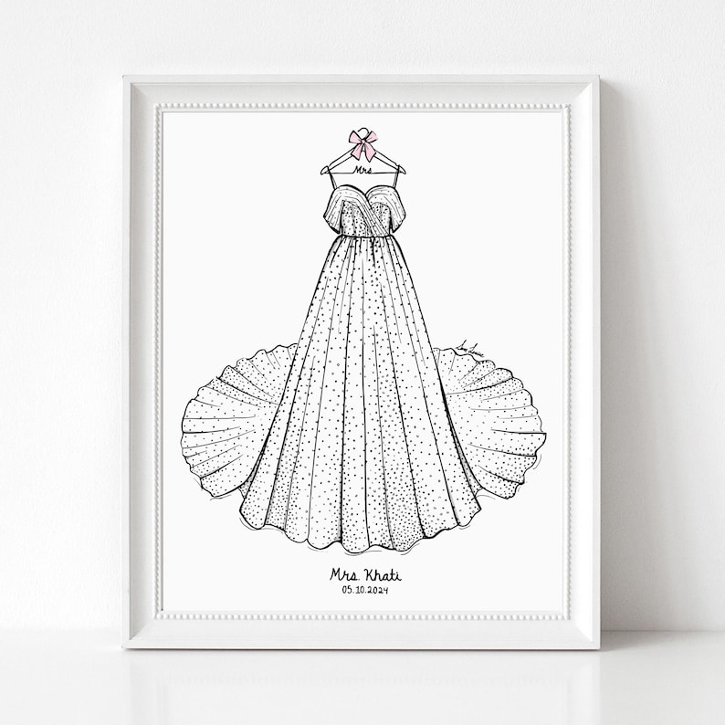 May include: A framed black and white line art illustration of a strapless gown with a full skirt and polka dot pattern, hanging on a hanger with a pink bow. The text Mrs. Khati and 05.10.2024 is printed at the bottom of the white paper.