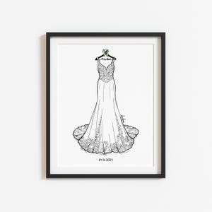 May include: A framed black and white line art illustration of a floor-length wedding dress on a hanger. The hanger features a small bow and the text Mrs. Rose. The date 04.06.2025 is printed at the bottom of the white paper within the black frame.