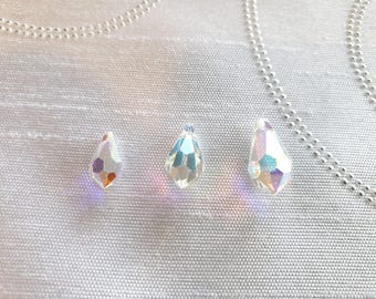 May include: Three clear teardrop-shaped crystal beads of varying sizes. The beads are iridescent and have a faceted design.