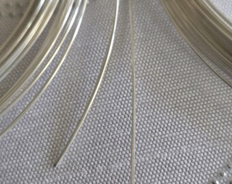 May include: Close-up of silver-colored wire coils. The image shows two different gauges of wire, with the text "22 gauge" and "24 gauge" displayed below the wires. The wires are on a textured, light-colored surface.