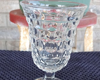 Peut inclure: Un gobelet en verre transparent avec un motif en diamant. Le gobelet a une base large et une tige haute et fine.