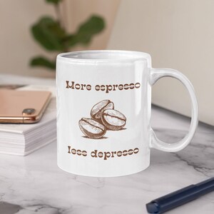 May include: White ceramic mug with a brown graphic of coffee beans and the text "More espresso less depresso".