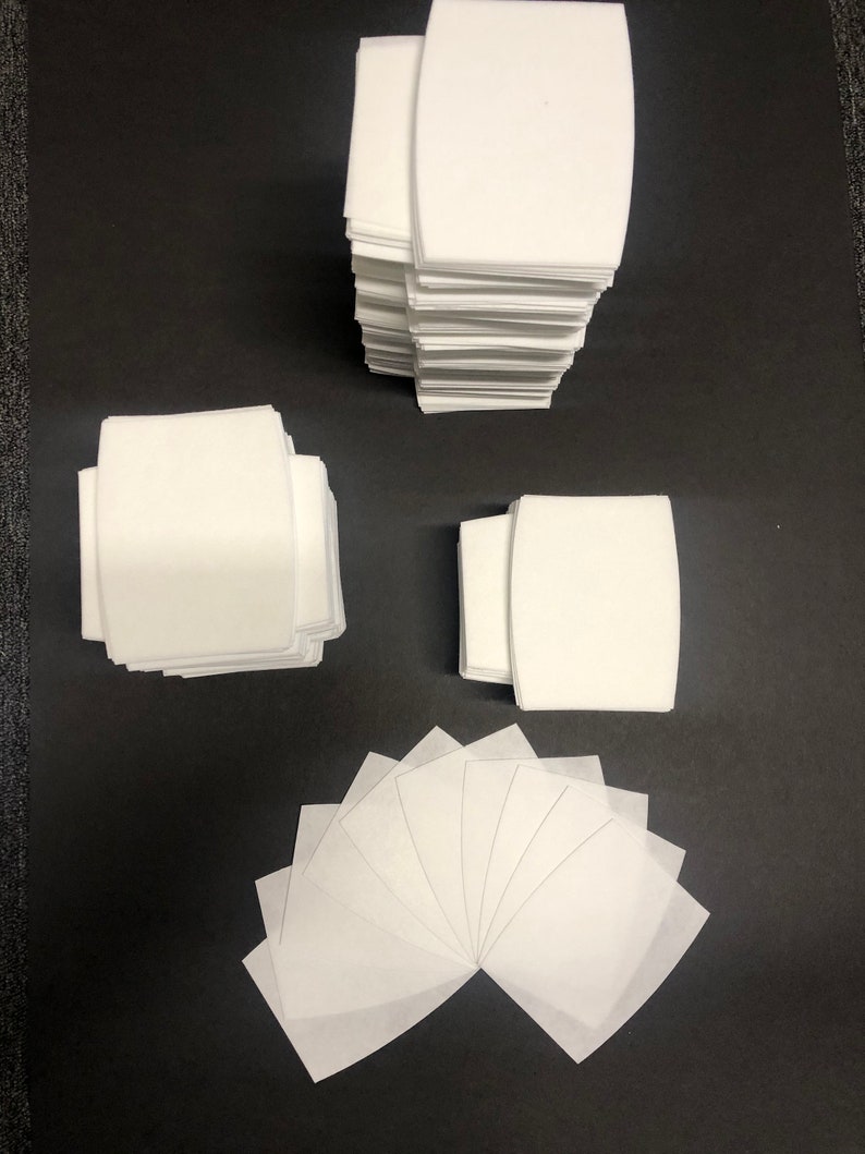 May include: A stack of white fabric squares, a stack of white fabric rectangles, and a fan of white fabric squares. The fabric squares and rectangles are all the same size and shape.