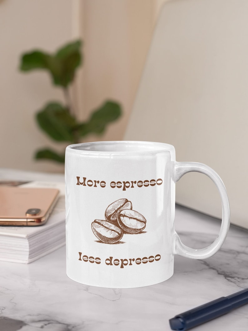 May include: White ceramic mug with a brown graphic of coffee beans and the text "More espresso less depresso".