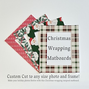 May include: A set of rectangular matboards featuring various holiday patterns including red with white snowflakes, green with holly berries, a Santa Claus print, and a beige plaid. The text "Christmas Wrapping Matboards" is centered on the plaid mat.