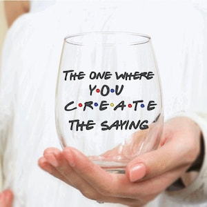 May include: A clear glass wine glass with the text "The One Where You Create The Saying" printed on it. The text is in a black font and is styled to look like the Friends logo.