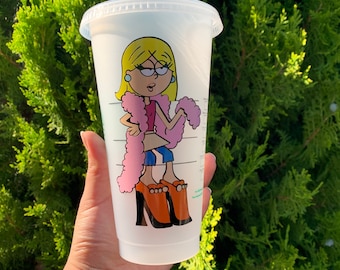 Op de afbeelding: Een witte herbruikbare beker met een cartoonillustratie van een blonde vrouw die een roze verenboa en oranje hakken draagt. De beker heeft een doorzichtig plastic deksel en een groene rietje.
