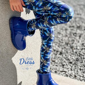 May include: Blue leggings with a dragonfly print. The leggings are worn with blue rain boots. The text "Little Dress Shoppe" is visible on the image.