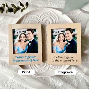 Peut inclure: Deux cadres photo en bois avec une photo de mariage d'un couple souriant. Les cadres portent l'inscription "To live together In the name of love" en bleu. L'un est étiqueté "Print" et l'autre "Engrave".