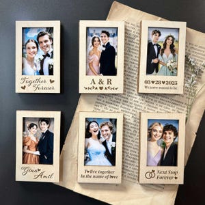 May include: A collection of wooden photo frames, each holding a wedding photograph. The frames feature various inscriptions such as "Together Forever," "A & R," and "Next Stop Forever." The photos are of couples.