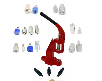 May include: A red metal snap press machine with a lever and a base. The machine is surrounded by various sizes of metal snaps, studs, and tools. The tools include a set of four black metal punches, a brass base, and a set of metal snap parts.