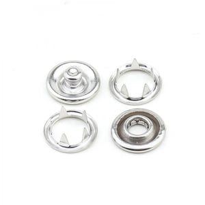 May include: A set of four silver-colored metal snap fasteners arranged in a square formation. The components include two circular caps with central studs or sockets and two matching pronged rings designed for fabric attachment and secure closure.