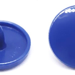 Peut inclure: Quatre boutons-pression en plastique bleu, deux avec un centre sur&eacute;lev&eacute; et deux plats.