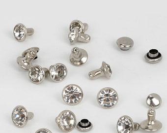 May include: Assortment of silver-toned metal and clear rhinestone embellishments. Some embellishments have a pronged back, while others have a flat back.