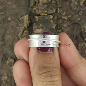 May include: A silver spinning ring with a hammered finish. The ring is engraved with the text "Artisan Turquoise Ring".