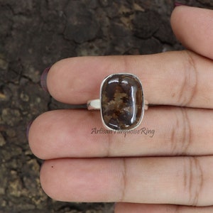 May include: A silver ring with a brown and white oval gemstone. The ring is set in a silver band and has a polished finish.