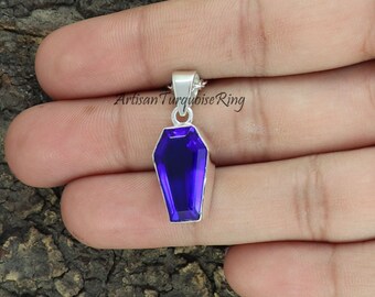 May include: A silver coffin pendant with a purple gemstone. The pendant is on a silver chain.