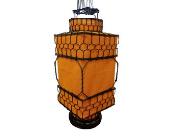 May include: A tall, orange lampshade with a black wire cage design. The lampshade is made of fabric and has a black metal base.