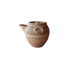 Puede incluir: Tetera de cerámica marrón con boquilla, tapa y dos asas curvas. La tetera tiene una superficie texturizada con bandas horizontales de color más claro. Diseño sencillo y rústico, ideal para servir té.