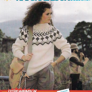 Puede incluir: Una mujer lleva un suéter blanco con un patrón geométrico gris y negro, pantalones marrones y un bolso de cuero marrón. El suéter está etiquetado como "Thermo-Knit" con el texto "Extra Warmth In" y "Machine Washable". El texto "Natural Look Colours!" también es visible en la imagen.