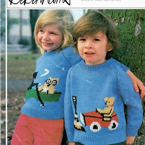 May include: Two children in light blue knitted sweaters with cartoon designs. One sweater shows a bear in a car, the other a bear in a boat. The sweaters are part of a Debenhams knitting pattern, sizes 51-66 cm.