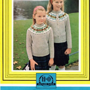 May include: Two young girls wearing Fair Isle circular yoke twin sets. The sweaters are light gray with colorful patterned yokes. They are paired with plaid skirts. The image is framed with a yellow border and includes text: "FAIR ISLE CIRCULAR YOKE TWIN SET."