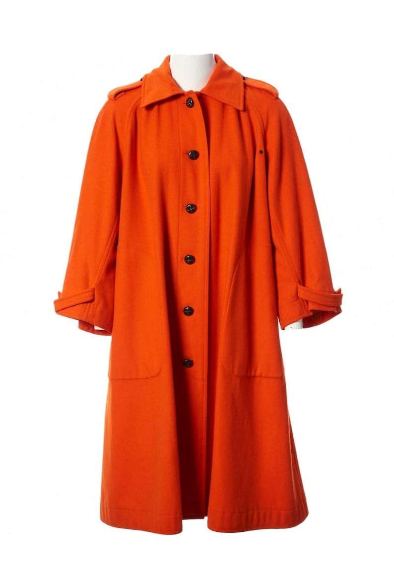 May include: A vibrant orange coat with a classic design. The coat features a collared neckline, black buttons, and long sleeves with cuff details. It has two front pockets and a tailored fit, perfect for outerwear.