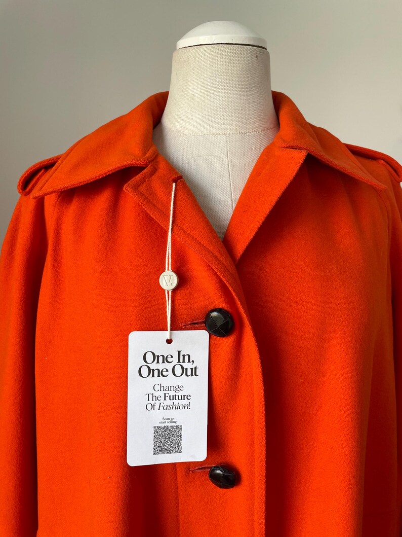 May include: Bright orange coat with a classic collar and black buttons. The coat features a tag that reads "One In, One Out, Change The Future Of Fashion!"