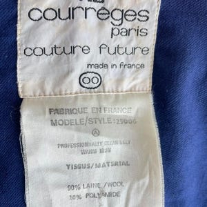 May include: Close-up of a white label with black text from Courr&egrave;ges Paris. The label reads "couture future" and "made in France." The label also includes fabric care instructions and material composition: 90% wool, 10% polyamide.