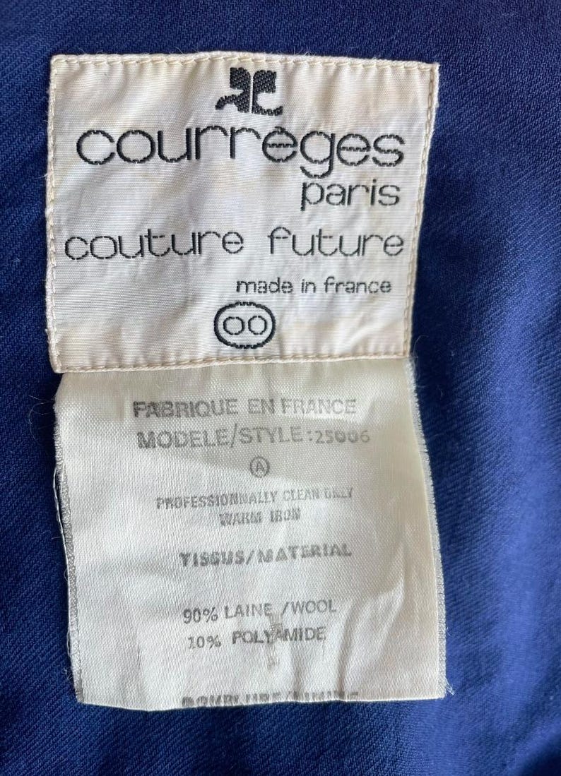 May include: Close-up of a white label with black text from Courr&egrave;ges Paris. The label reads "couture future" and "made in France." The label also includes fabric care instructions and material composition: 90% wool, 10% polyamide.
