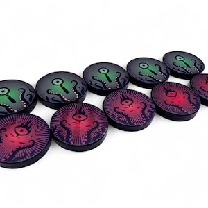 May include: A collection of ten round game tokens. Five tokens feature a red eye design with tentacles, while the other five have a green magnifying glass and tentacles. The tokens have a black border and a gradient background.