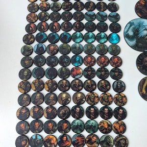 K&ouml;nnte beinhalten: Eine Sammlung runder Spielsteine mit Portr&auml;ts von Fantasy-Charakteren. Die Steine zeigen eine Vielzahl von Charakteren mit detaillierten Kunstwerken, darunter Zauberer, Monster und Krieger. Die Steine sind auf einer wei&szlig;en Oberfl&auml;che angeordnet.