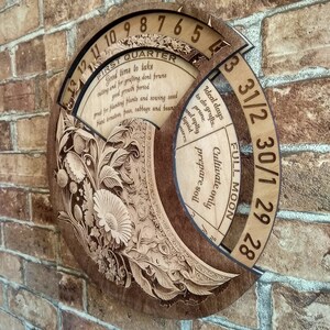 Peut inclure: Un calendrier circulaire en bois avec un motif floral et les mots "Premier trimestre" et "Pleine lune". Le calendrier comporte les num&eacute;ros de 1 &agrave; 31 et le texte "Jours id&eacute;aux pour faire des greffes. Tailler et appliquer des rem&egrave;des liquides. Cultiver uniquement pr&eacute;parer le sol."