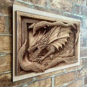 May include: A wooden wall art piece featuring a detailed carving of a dragon with its wings spread wide. The dragon is set within a frame with intricate carvings around the edges.
