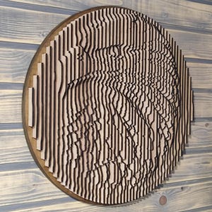 May include: A round wooden wall art piece with a layered design. The artwork features vertical, dark brown lines on a light brown background, creating a textured, three-dimensional effect. The piece is mounted on a circular wooden base.