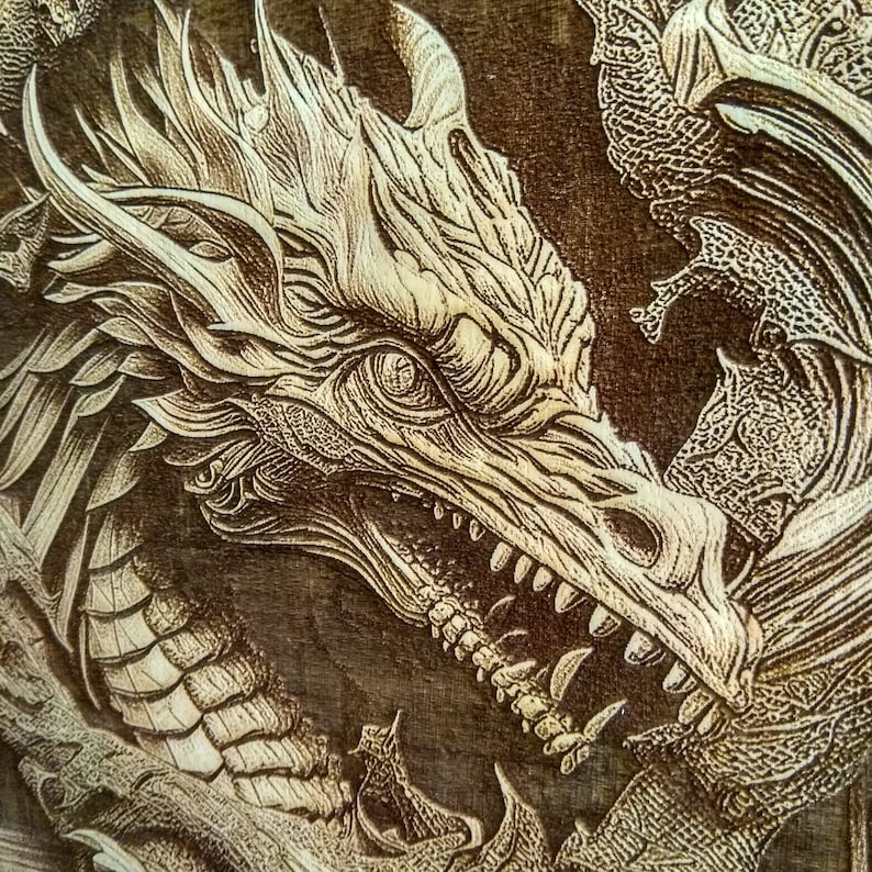 May include: A close-up of a wood-burned dragon design. The dragon is depicted with an open mouth, showing sharp teeth, and a detailed, intricate design.