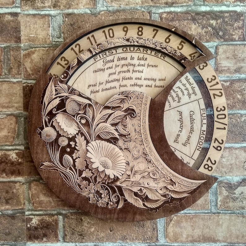 Peut inclure: Un calendrier circulaire en bois avec un motif floral. Le calendrier est divis&eacute; en sections pour chaque mois de l'ann&eacute;e. Le calendrier comprend &eacute;galement une section pour les phases de la lune. Le texte sur le calendrier indique "Premier trimestre", "Bon moment pour prendre des boutures et pour le greffage, ne pas tailler", "bonne p&eacute;riode de croissance", "id&eacute;al pour planter des plantes et semer des graines", "planter des tomates, des pois, du chou et des haricots", "Pleine lune", "Jours id&eacute;aux pour faire des greffes, tailler", "et appliquer du liquide", "Cultiver uniquement", "pr&eacute;parer le sol".