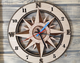 May include: A wooden compass clock with a brown and white design. The clock face features a compass rose with the letters N, S, E, and W. The clock hands are black and red. The clock face also has a tide chart with the words "High Tide", "Half Tide", and "Low Tide".