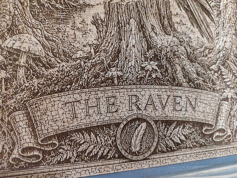 May include: A detailed wood-engraved illustration featuring a forest scene with a tree stump, mushrooms, and ferns. A prominent banner across the bottom displays the text THE RAVEN in capital letters, with a circular emblem containing a feather.