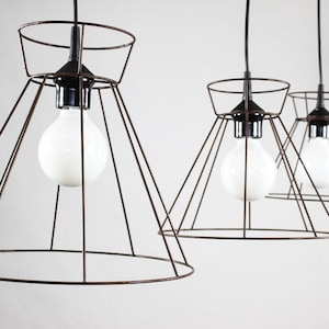 May include: Three black wire cage pendant lights with white light bulbs hanging from the ceiling.