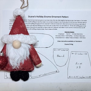 May include: A handmade Christmas gnome ornament with a red hat and coat, white beard, and a red glitter ball. The gnome is holding a red ornament. The pattern sheet shows measurements in inches.