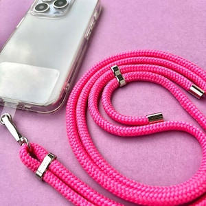 May include: A bright pink phone strap with silver hardware. The strap is made of a thick, braided cord and is long enough to wear around the neck.