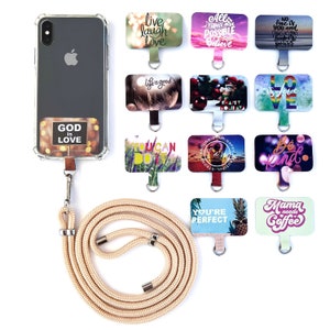 Peut inclure: Une dragonne de téléphone beige avec un étui de téléphone transparent orné d'un autocollant doré et blanc qui dit "Dieu est Amour". L'étui de téléphone est relié à la dragonne par un anneau métallique. Il y a 10 breloques de téléphone carrées colorées avec des messages inspirants, tels que "Vivre Rire Aimer", "Tu peux le faire", et "Tu es parfait".