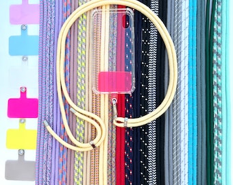 May include: A variety of colorful phone straps made of braided rope, with a clear phone case and a lanyard attached. The phone straps are arranged in a row, with the phone case and lanyard in the center.
