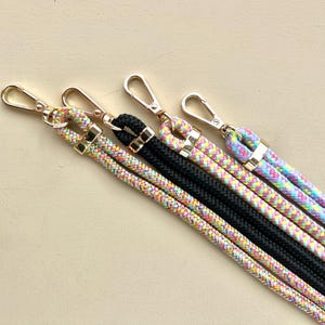 Puede incluir: Cuatro correas de tel&eacute;fono de cuerda trenzada de colores con cierres dorados. Las correas son de color rosa, amarillo, verde y azul.