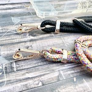 May include: Two phone straps with gold clasps. One strap is black and the other is multi-colored with pink, yellow, and purple.