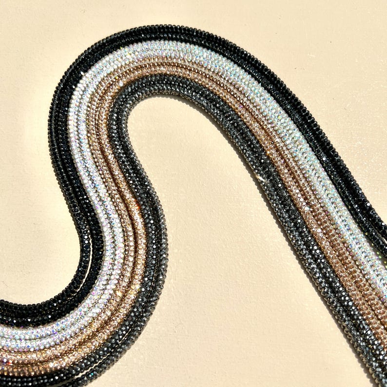 May include: A set of six rhinestone chains in black, gray, silver, gold, and two shades of iridescent white.