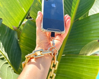 May include: A clear phone case with a gold chain attached to it. The chain is wrapped around a person's wrist.