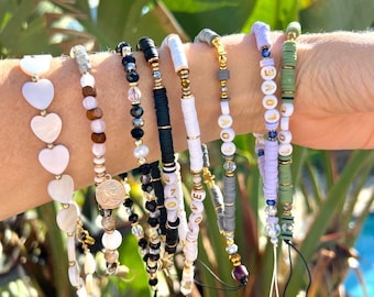 May include: A set of colorful beaded bracelets with gold accents. The bracelets feature different patterns, including hearts, beads, and the word "LOVE".