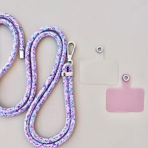 Może przedstawiać: Kolorowy pleciony sznurek z klamrą srebrną i dwoma przezroczystymi plastikowymi uchwytami na identyfikator. Jeden uchwyt jest przezroczysty, a drugi jasnoróżowy.